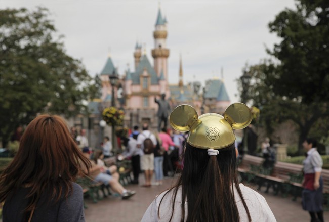 In this Jan. 22, 2015, file photo, a woman with a Mickey Mouse hat walks toward Sleeping Beauty's Castle at Disneyland, in Anaheim, Calif.