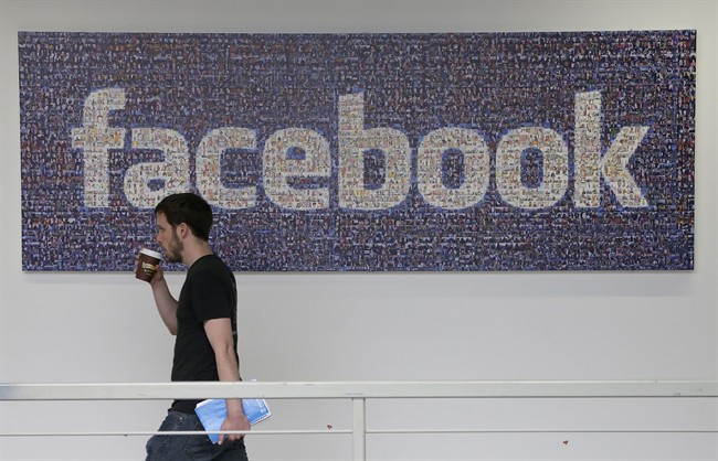  In this March 15, 2013, file photo, a Facebook employee walks past a sign at Facebook headquarters in Menlo Park, Calif. 
