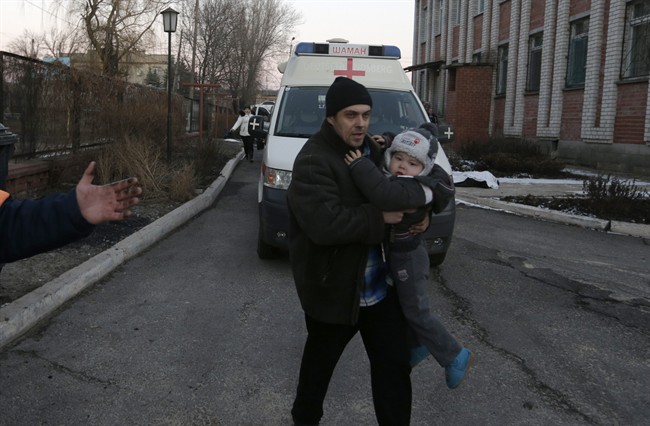 A man carries a child after shelling between Russia-backed separatists and Ukrainian government forces in a residential area of the town of Artemivsk, Ukraine, Friday, Feb. 13, 2015. 