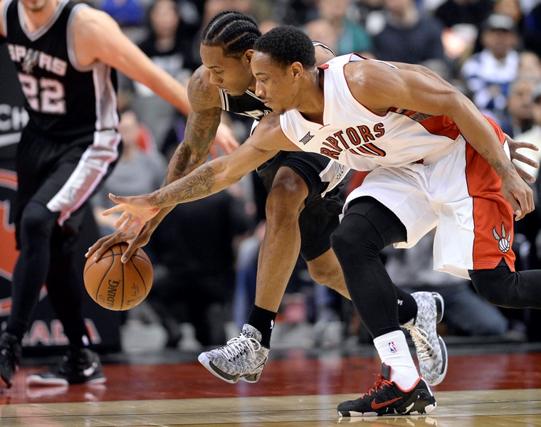 San Antonio Spurs' Kawhi Leonard, left, chases the ball with Toronto Raptors' DeMar DeRozan during the first half of an NBA basketball game, Sunday, Feb. 8, 2015, in Toronto.