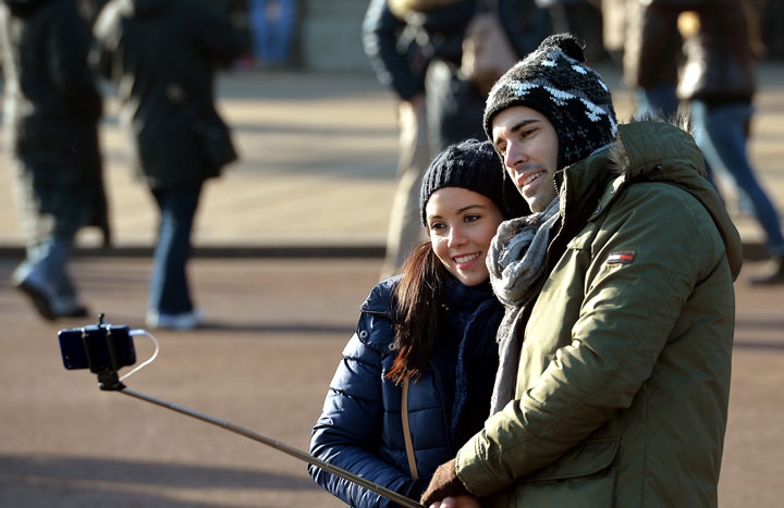 Tourists use a 'selfie stick' to take a self-portrait.