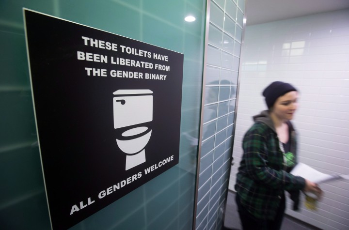 A protester for transgender rights walks out of a men's washroom.