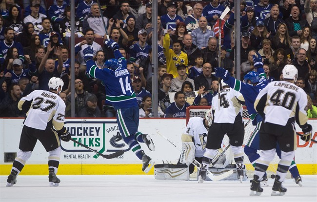 Vancouver Canucks' Alex Burrows (14) celebrates his goal against Pittsburgh Penguins' goalie Thomas Greiss, of Germany, (1) as Craig Adams (27), Rob Scuderi (4) and Maxim Lapierre (40) watch during the first period of an NHL hockey game in Vancouver, B.C., on Saturday February 7, 2015.