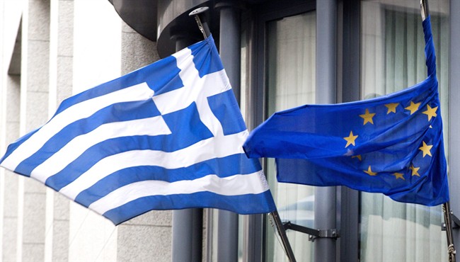 The Greek, left, and EU flag flap in the wind outside the Greek embassy in Brussels on Friday, Feb. 20, 2015. 