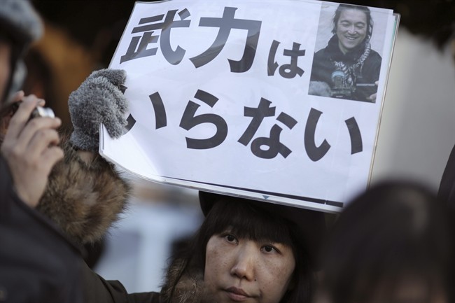A woman sympathizer for Japanese hostage Kenji Goto holds a sign stating: "We do not need armed forces" and bearing his photo in front of the prime minister's official residence in Tokyo Sunday, Feb. 1, 2015 after an online video purporting to show an Islamic State group militant beheading Goto was circulated via social media.