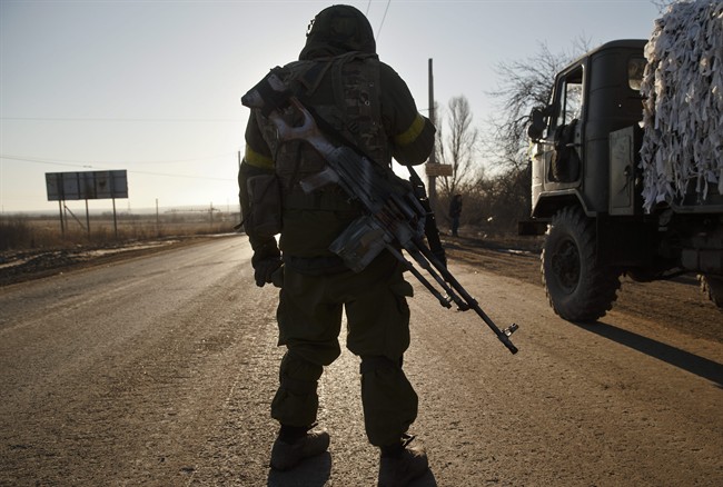 A Ukrainian serviceman stands on the road outside Artemivsk, Ukraine, after pulling out of Debaltseve, Wednesday, Feb. 18, 2015.