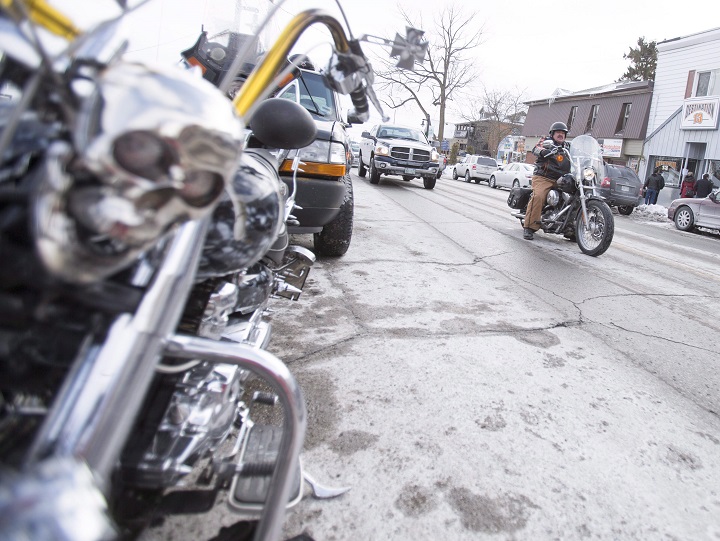 FILE PHOTO - One of the few motorcycles to brave the cold weather for their Friday the 13th celebrations drives by a another bike in downtown Port Dover, Ont., Friday, Feb. 13, 2015.