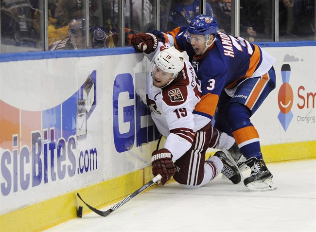 Arizona Coyotes right wing Shane Doan (19) and New York Islanders defenceman Travis Hamonic (3) battle for the puck against the boards in the third period of an NHL hockey game at Nassau Coliseum on Tuesday, Feb. 24, 2015.