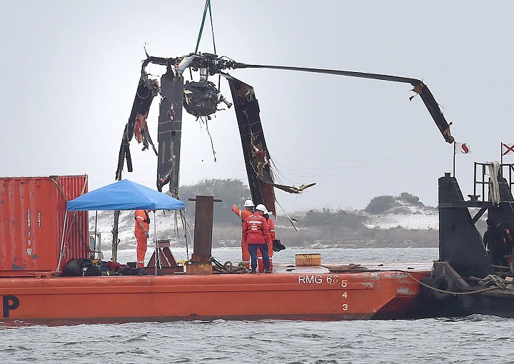 Crews lower a piece of a Black Hawk helicopter onto a barge in the Santa Rosa Sound near Pritchard Point, Friday, March 13, 2015, in Navarre, Fla.