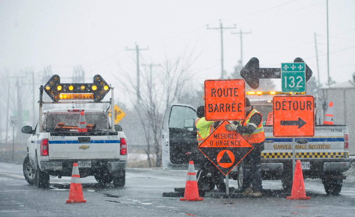 Workers set up a road block in the town of Varennes, Que.,