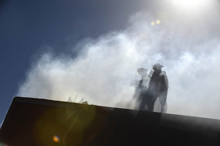 Silhouetted by smoke, firefighters work on the roof of a Toronto townhouse in April, 2014. (FRED LUM/THE GLOBE AND MAIL)