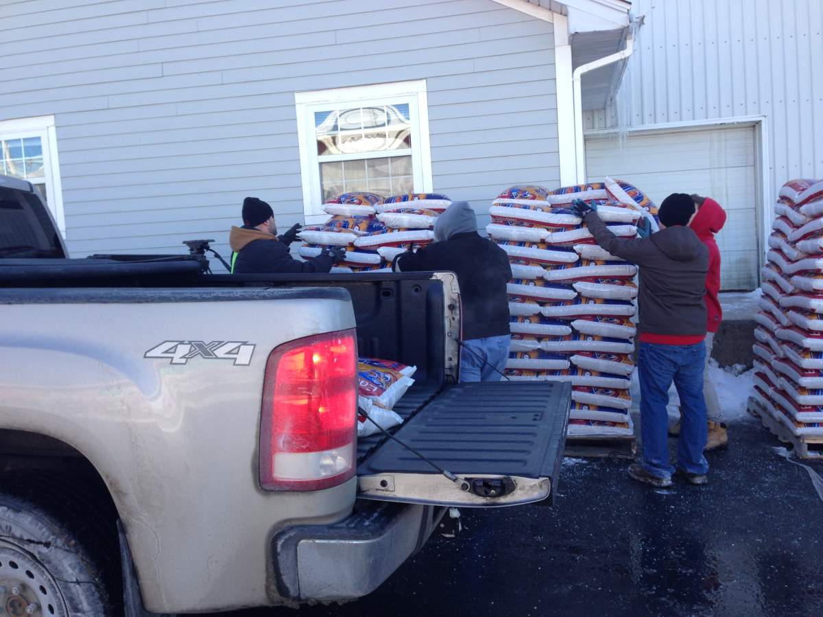 Employees load bags of wood pellets into vehicles.