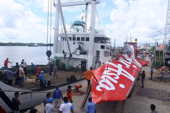 Workers load the tail of AirAsia flight QZ8501 onto a truck at Kumai sea port, in Central Kalimantan, on February 7, 2015 before they transport it to Jakarta.  Indonesian divers found a body believed to belong to the French co-pilot of the AirAsia plane that crashed late December with 162 people on board, an official said.  