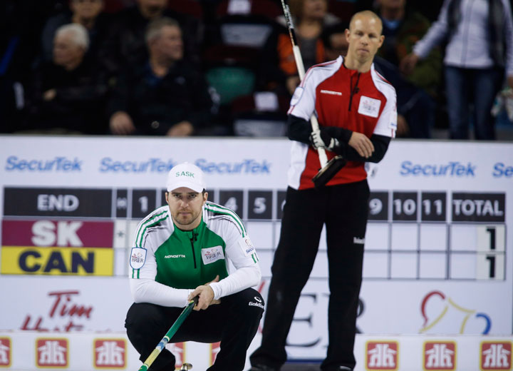 Saskatchewan skip Steve Laycock, left, lines up a shot as Team Canada skip Pat Simmons looks on during playoff curling action at the Brier in Calgary, Saturday, March 7, 2015.