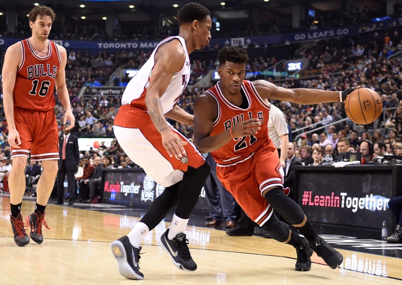 Chicago Bulls' Jimmy Butler (21) drives along the base line as Toronto Raptors' DeMar DeRozan defends first half NBA basketball action in Toronto on Wednesday, March 25, 2015. 
