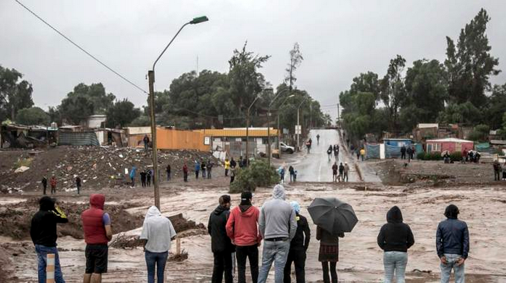 Residents watch the rising flood waters of the Copiapo River, in Copiapo, Chile, Wednesday, March 25, 2015. Unusually heavy thunder storms and torrential rains that began on Tuesday have blocked roads, caused power outages and affected some 600 people on this normally dry region.