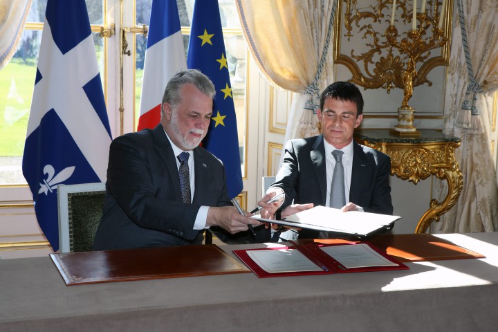 French Prime Minister Manuel Valls, right, and Quebec Premier Philippe Couillard exchange documents as they sign agreements, following their meeting at the Hotel Matignon in Paris, Friday March 6, 2015.