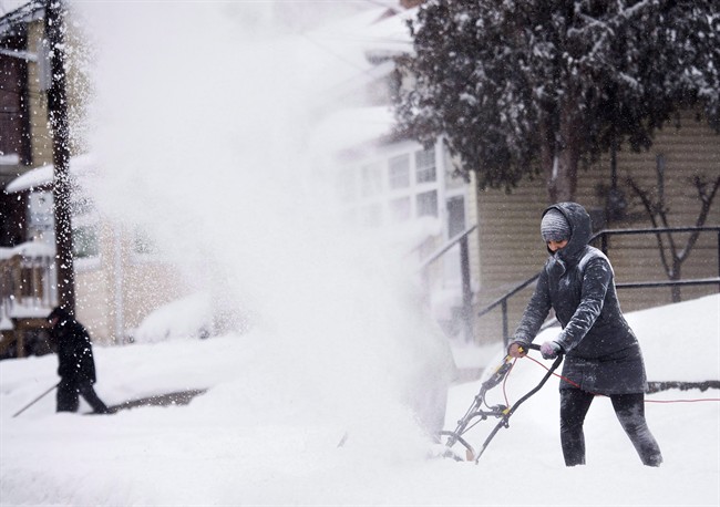 People clear snow from their sidewalks and streets after a large amount of snow fell in Toronto on Monday, February 2, 2015.