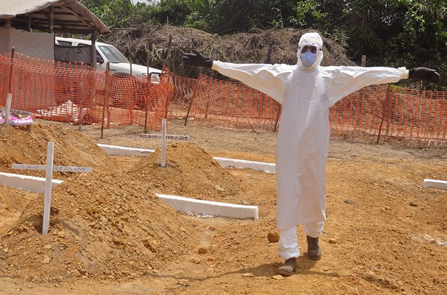 In this photo taken on Wednesday, March 11, 2015, a health worker holds up his arms after he and others buried a person that they suspect died form the Ebola virus at a new graveyard on the outskirts of Monrovia, Liberia.