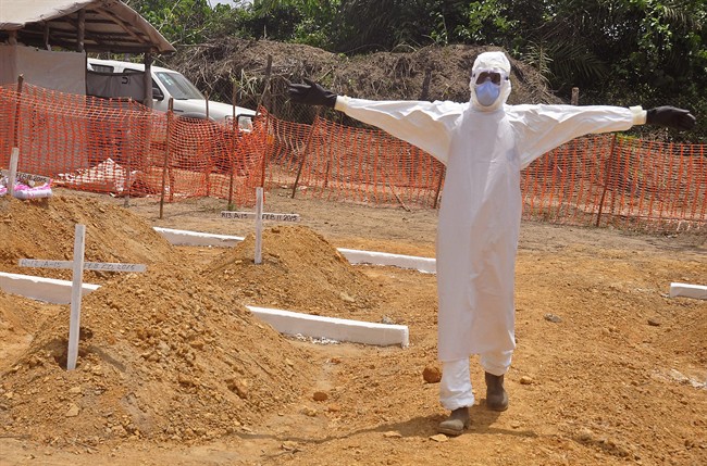 In this photo taken on Wednesday, March 11, 2015, a health worker holds up his arms after he and others buried a person that they suspect died form the Ebola virus at a new graveyard on the outskirts of Monrovia, Liberia. 
