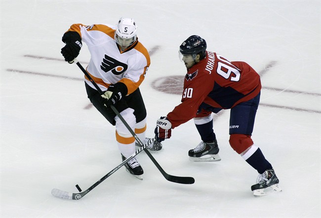 Washington Capitals' Marcus Johansson and Philadelphia Flyers' Braydon Coburn battle for the puck during the first period of a NHL preseason hockey game in Washington on Oct. 2, 2014.