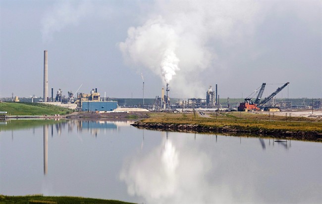 An oil sands facility is reflected in a tailings pond near Fort McMurray, Alta., on July 10, 2012. 