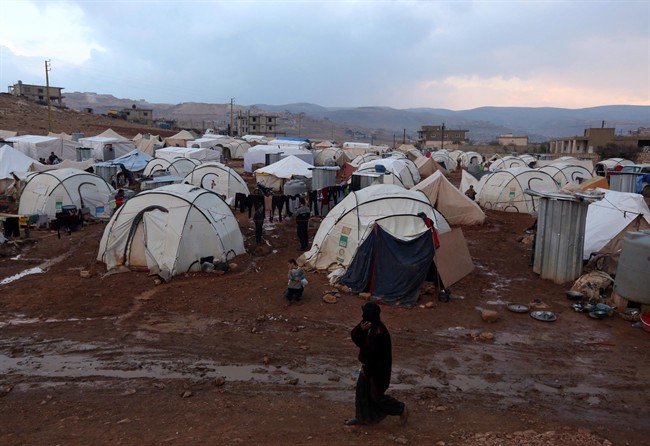 Canada is being called upon to pledge nearly $180 million towards a record-breaking international aid appeal for Syria this year. A Syrian refugee woman walks near the tents of a refugee camp in the eastern Lebanese border town of Arsal in this Monday, Nov. 18, 2013 file photo.