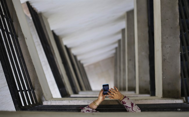 An Indian woman leans on metal railings as she surfs the internet on her smartphone at a hospital in New Delhi, India, Tuesday, March 24, 2015. India's top court reaffirmed people's right to free speech in cyberspace Tuesday by striking down a provision that had called for imprisoning people who send "offensive" messages.
