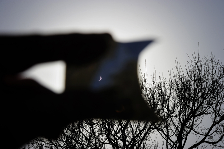 A man uses a protective slide to watch as the moon passes in front of the Earth’s star marking a total eclipse, the only one this year, in Vigo, northwestern Spain on March 20, 2015.