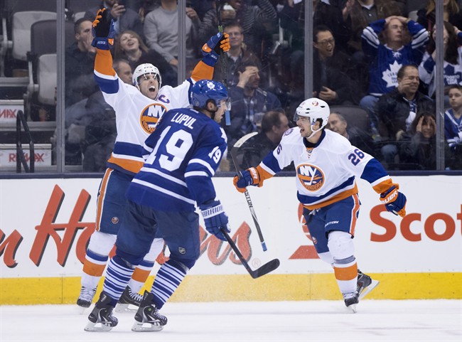 Toronto Maple Leafs' Joffrey Lupul, centre, reacts as New York Islanders' John Tavares, left, celebrates with teammate Tyler Kennedy after scoring the game winning goal during the overtime period of NHL action in Toronto on Monday March 9, 2015.