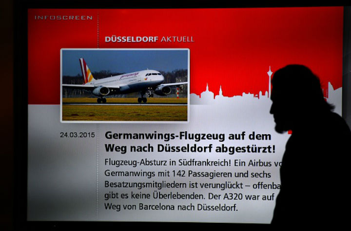 A man walks past a screen displaying news on the crash of a Germanwings plane on March 24, 2015 at the airport in Duesseldorf, western Germany, where the crashed Germanwings airplane was due to land. 