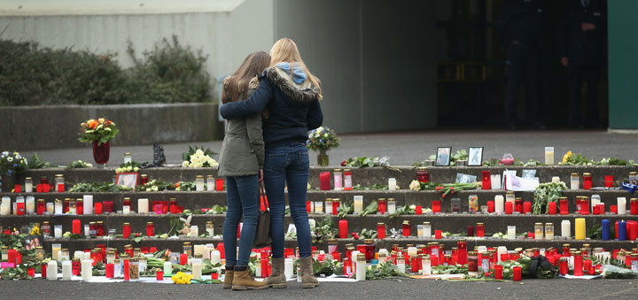 Two young women comfort one another while looking at flowers and candles left by mourners at the Joseph-Koenig-Gymnasium high school to pay tribute to 16 students and two teachers from the school who were on Germanwings flight 4U9525 that crashed yesterday in southern France on March 25, 2015 in Haltern, Germany. 