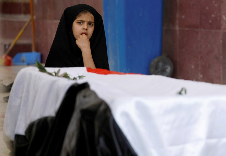 Mariam Ali, 5, sits next to the flag-draped coffin of her brother Ahmed Ali, 6, who was killed in a car bomb attack in Najaf, south of Baghdad, Iraq, in Mar. 2014. The U.N. says at least 1,100 Iraqis were killed in February, including more than 600 civilians.