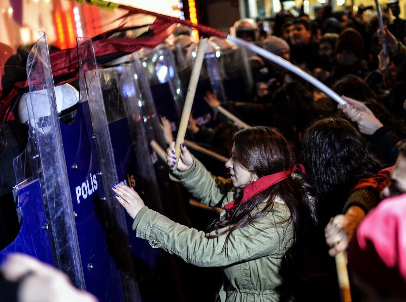 Turkish women beat riot police shields on March 8, 2015 as they try to cross a police cordon to reach Taksim square during a rally on Istiklal avenue in Istanbul to mark International Women's Day. 