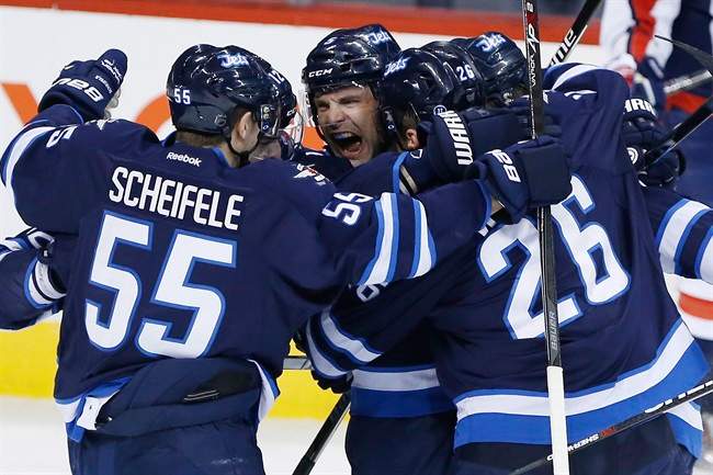 Winnipeg Jets' Mark Scheifele (55), Mark Stuart (5) and Blake Wheeler (26) celebrate Stuart's goal against the Washington Capitals during first period NHL action in Winnipeg on Saturday, March 21, 2015.