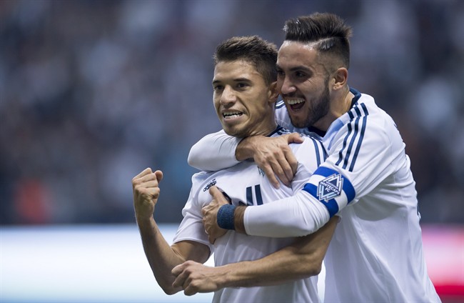 Vancouver Whitecaps FC's Nicolas Mezquida, left, celebrates his goal with teammate Pedro Morales against the Portland Timbers during the first half of MLS soccer action in Vancouver, B.C. Saturday, March 28, 2015. THE CANADIAN PRESS.