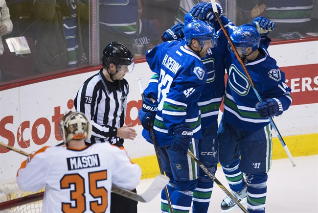 Vancouver Canucks' Alex Burrows (14) celebrates his goal with Daniel Sedin and Henrik Sedin as Philadelphia Flyers goalie Steve Mason (35) looks on during the third period of NHL action in Vancouver, B.C. Tuesday, March. 17, 2015.