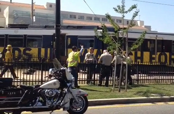 In this still image from a video, fire and police members work near a derailed commuter train that struck a car Saturday, March 28, 2015, in Los Angeles. 
