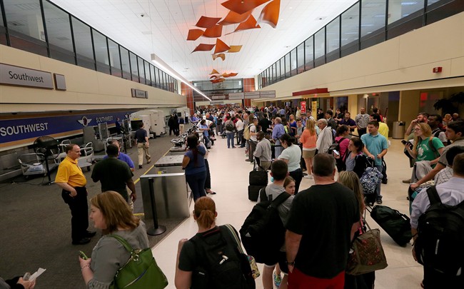 Long lines of travellers await word of their departures in the ticketing area of Louis Armstrong International Airport after a machete-wielding man was shot by a TSA employee on Friday, March 20, 2015.