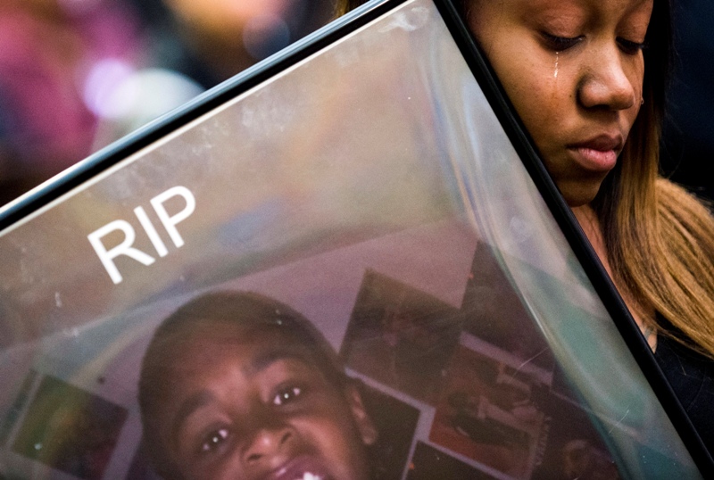 Andrea Washington holds a photo of her son Trashawn Macklin, who was killed in July 2013, while listening to Freeman Elementary teacher Laura Garrison speak about Macklin, Monday, March 2, 2015, in Flint, Mich., during the sentencing of Deonte Gray. Gray was convicted on three first-degree premeditated murder charges, including the death of Macklin, and sentenced to life in prison without parole. 