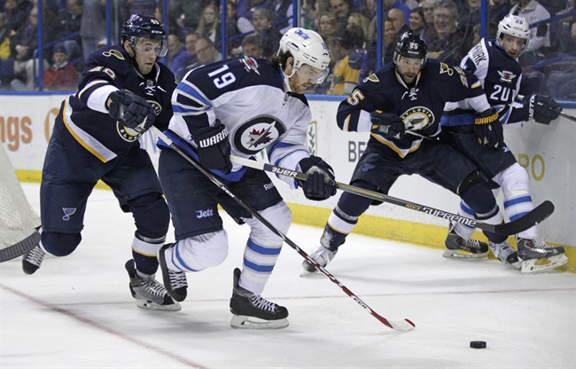 St. Louis Blues' Petteri Lindbohm tries to poke the puck away from Winnipeg Jets' Jim Slater during NHL action. 