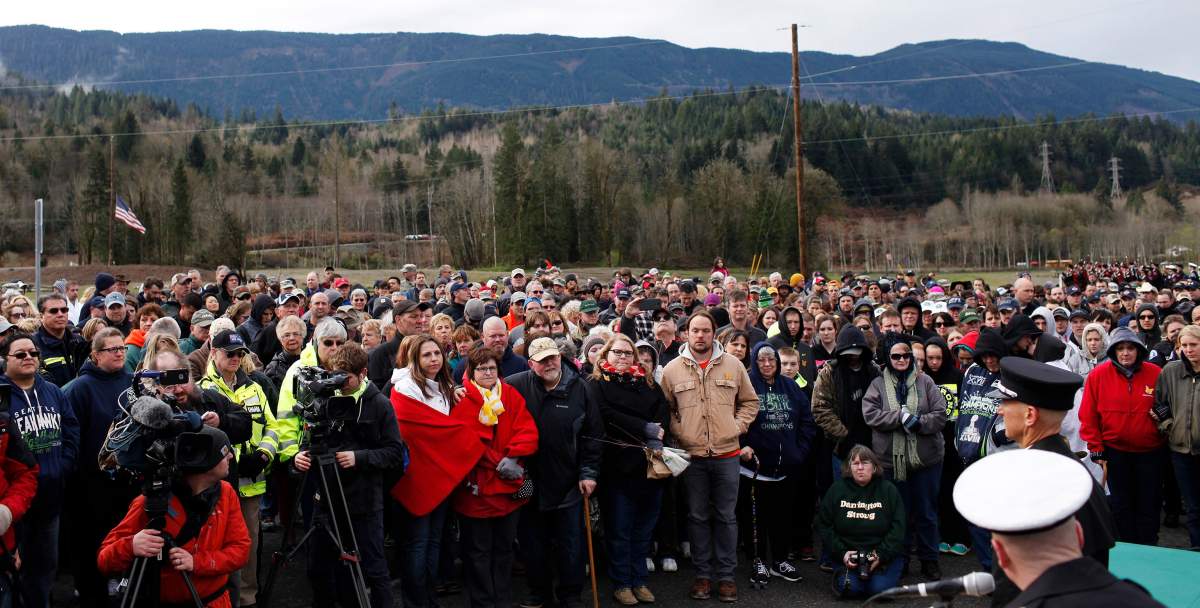 People gather Sunday morning, March 22, 2015, at the former entrance to Steelhead Haven for a ceremony commemorating the one-year mark since the Oso, Wash., landslide. A solemn crowd gathered to honor 43 people who lost their lives a year ago in the deadliest landslide in U.S. history. A moment of silence was observed at 10:37 a.m. at the site on Highway 530. (AP Photo/The Daily Herald, Genna Martin)