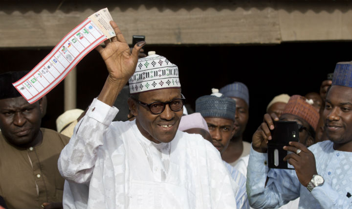 In this Saturday, March 28, 2015 file photo, opposition candidate Gen. Muhammadu Buhari holds his ballot paper in the air before casting his vote in his home town of Daura, northern Nigeria. 