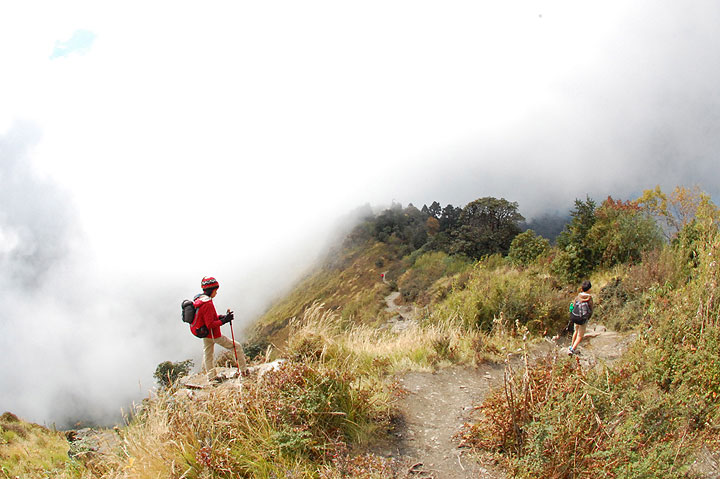 In this Thursday, Oct. 23, 2014, photo, clouds waft across the trail along a ridge above the village of Ghorepani, in central Nepal. Some travelers hire a porter to help carry gear and allow trekkers to travel with smaller knapsacks.