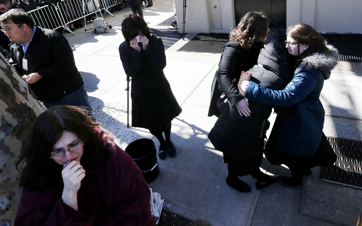 A woman is consoled and others cry as vehicles carrying the remains of the seven siblings killed in a house fire depart after funeral services, Sunday, March 22, 2015, in the Brooklyn borough of New York. 