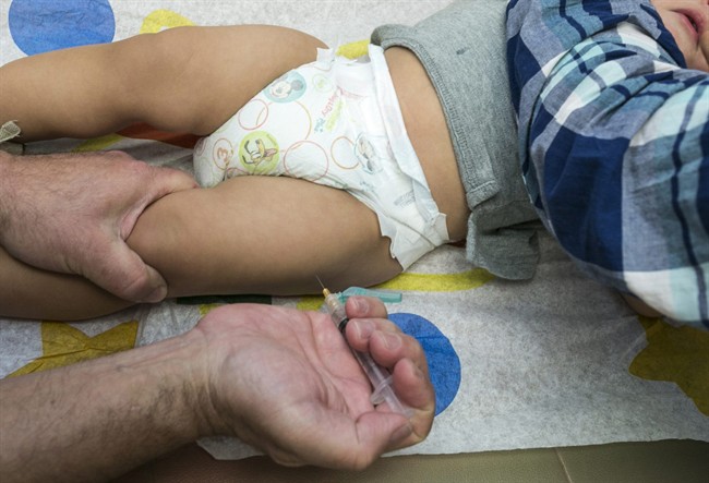 In this Jan. 29, 2015 file photo, a pediatrician uses a syringe to vaccinate a 1-year-old with the measles-mumps-rubella (MMR) vaccine.