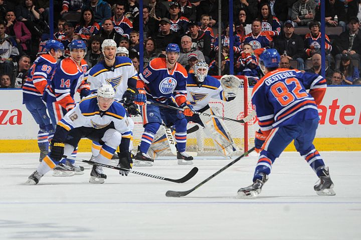  Jordan Oesterle #82 of the Edmonton Oilers takes a shot as Jori Lehtera #12 and Brian Elliott #1 of St. Louis Blues attempt to block the shot on February 28, 2015 at Rexall Place in Edmonton, Alberta, Canada.