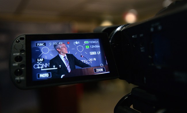 CTRC Chairman Jean-Pierre Blais is pictured in the screen of a reporters camera as he is filmed speaking to media at the CRTC offices in Gatineau, Que., on Thursday, March 19, 2015. THE CANADIAN PRESS/Sean Kilpatrick
