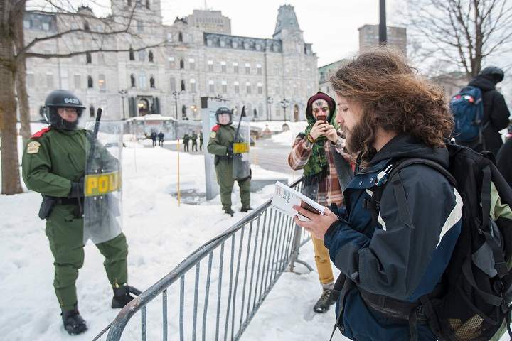 A protester reads poetry to a policemen during a protest against austerity organized by the ASSE student group in Quebec City, Thursday, March 26, 2015.