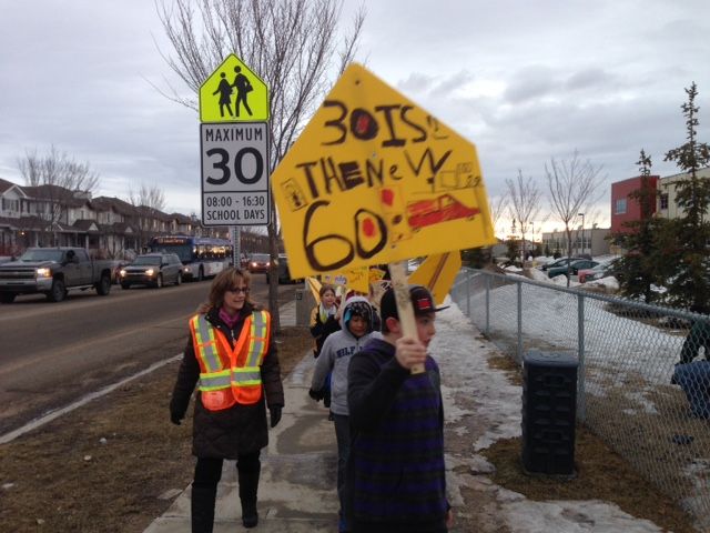 Children outside an Edmonton school hold a rally to remind drivers to adhere to the school zone speed limit, Monday, March, 9, 2015. 